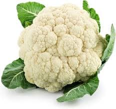 Fresh organic cauliflower with tightly packed white florets and green leaves, placed in a kitchen setting ready for healthy and tasty cooking.
