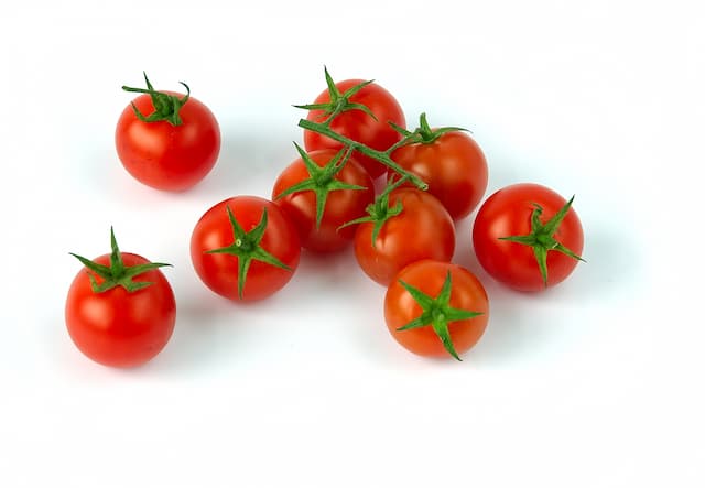 Bright red organic cherry tomatoes still on the vine—juicy, sweet, and hand-harvested from our exotic vegetable collection.