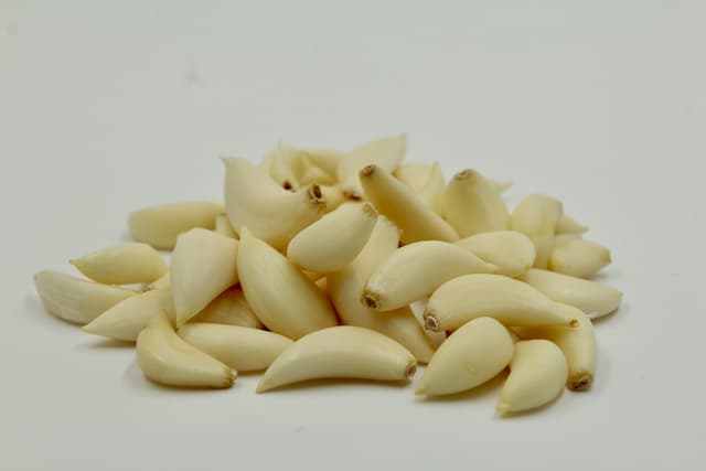 A bowl of fresh, organic peeled garlic cloves neatly arranged—ready-to-use, chemical-free, and part of our exotic vegetable range.