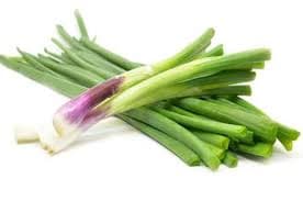 A bunch of fresh, organic spring onions (kanda patta) with green stalks and white bulbs placed on a rustic wooden surface for healthy cooking.